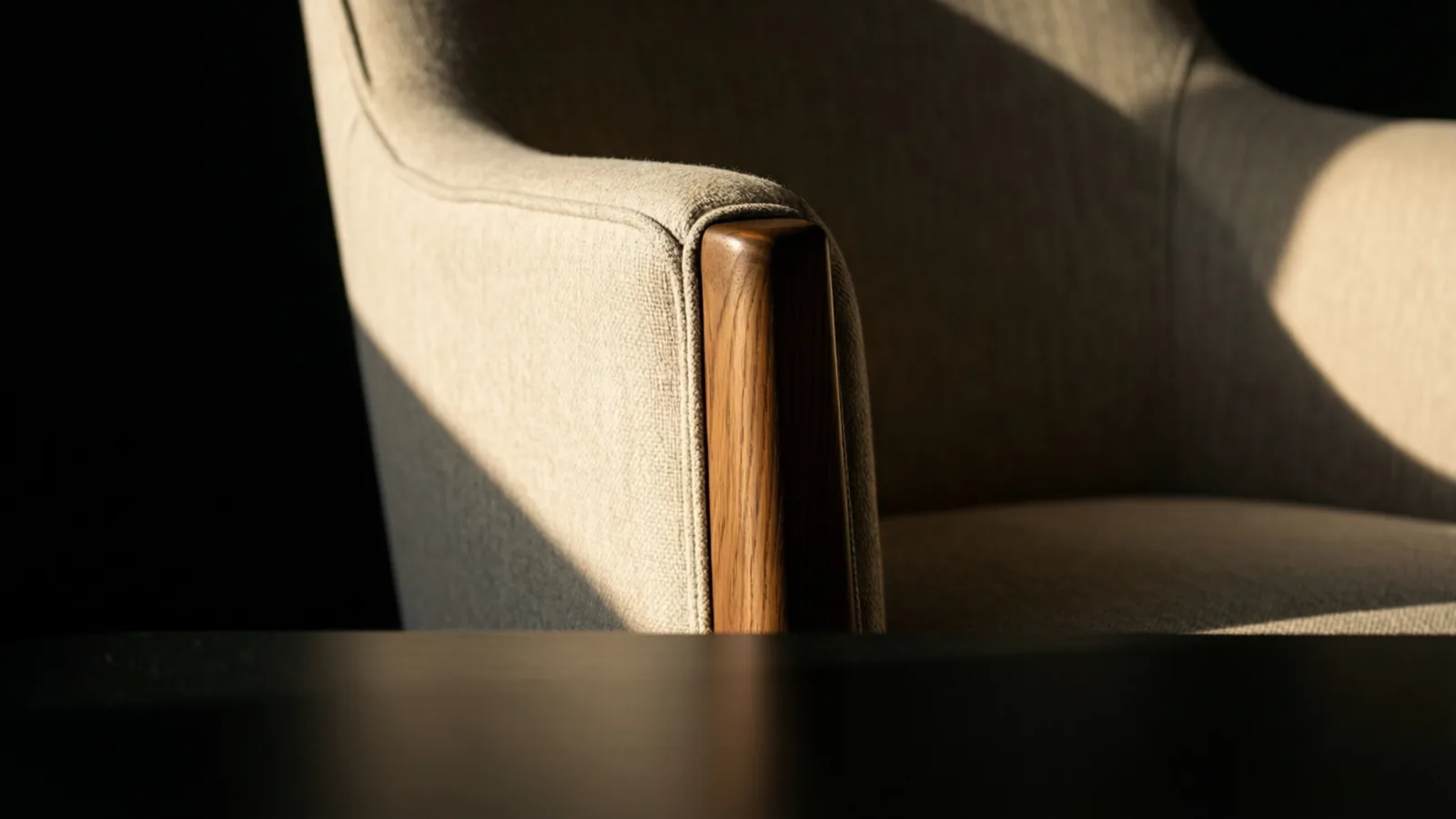 Close detail of an oak chair leg meeting a wool-upholstered frame